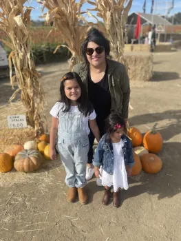 Dora poses with her two daughters with pumpkinds and cornstalks