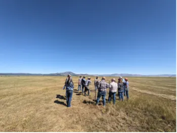 Ranchers gather in a pasture under a blue sky